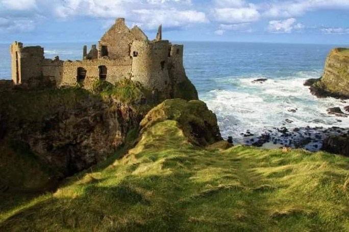 a stone castle next to a body of water with Dunnottar Castle in the background